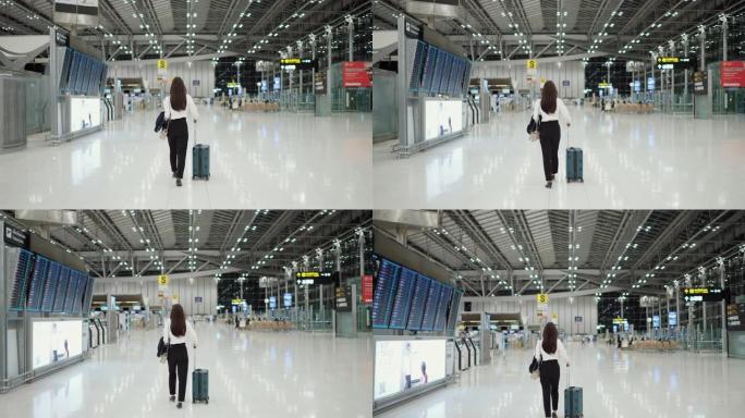 穿着制服的女雇主拉着行李箱在机场航站楼散步