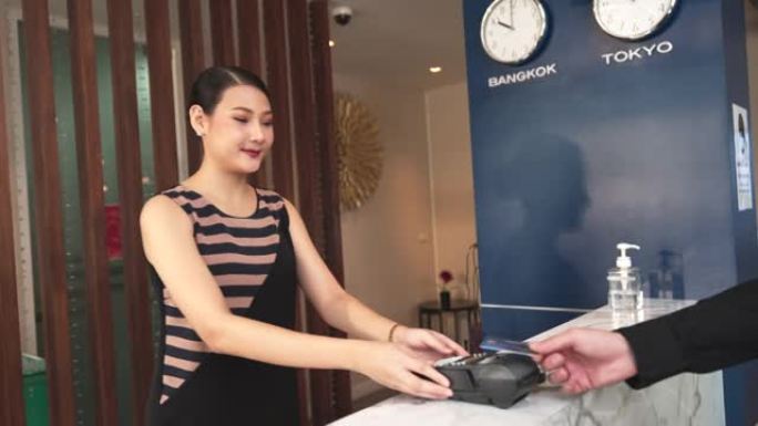 酒店工作人员正在向使用该服务的酒店客户处理信用卡机。支付商品或服务的费用。是没有现金的交易。它显示了