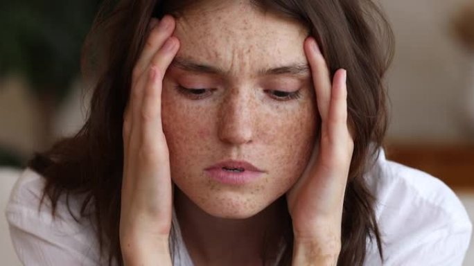 年轻女子的雀斑脸触及太阳穴患有头痛