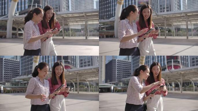 两个亚洲女商人朋友在城市的智能手机上分享了一些东西