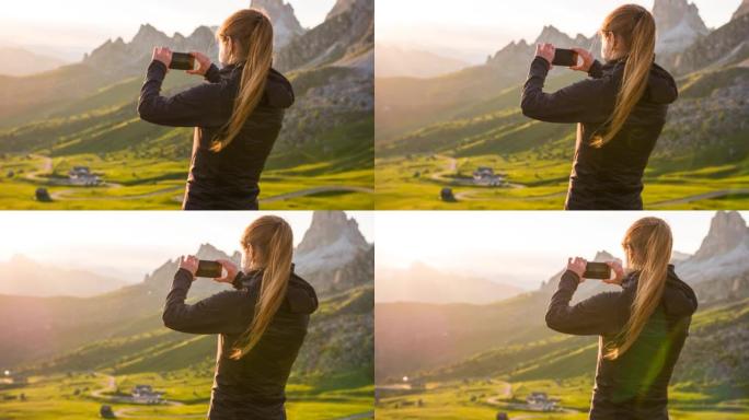女人俯瞰山谷，用智能手机拍摄日落时令人难以置信的风景