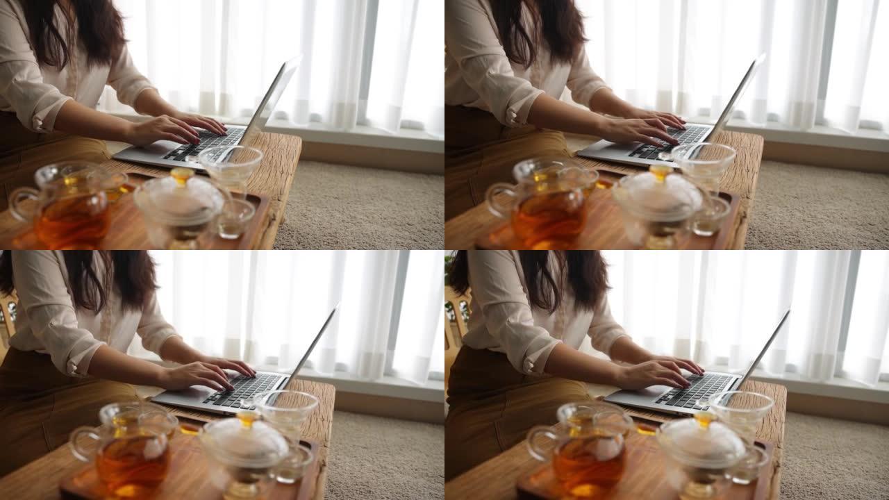 用茶杯在笔记本电脑上工作的女性特写