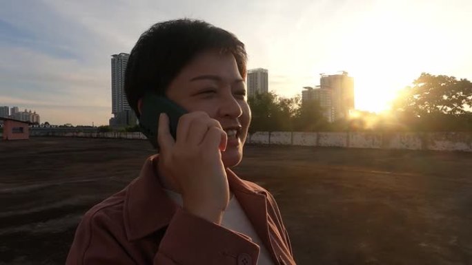 亚洲中国中年妇女晚上在电话里在户外微笑
