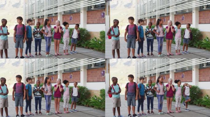 各种各样的学童穿着背包微笑着站在学校院子里排成一排
