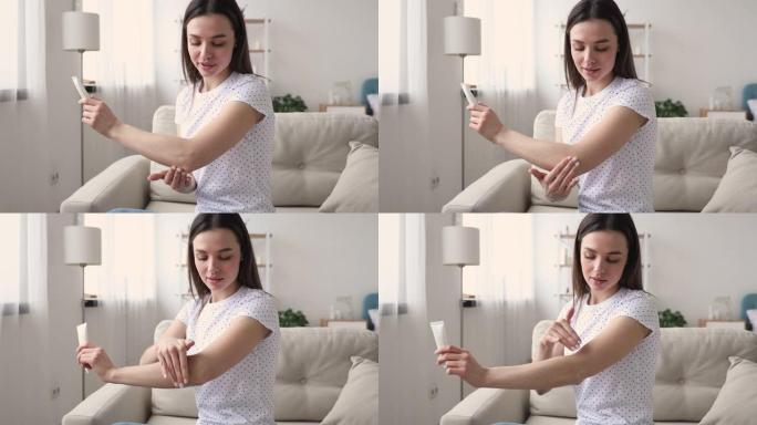 年轻迷人的女人在肘部涂抹保湿霜。