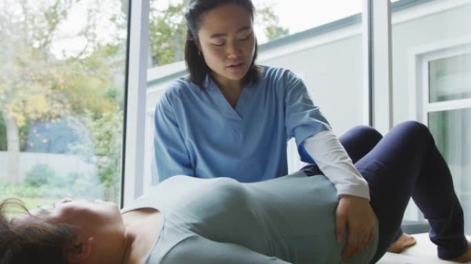 亚洲女性理疗师治疗躺在手术检查床上的女性患者