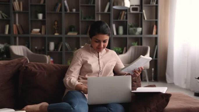 印度学生坐在笔记本电脑的沙发上进行作业