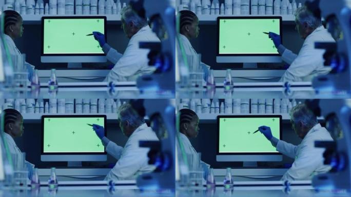 研究人员分析和讨论实验结果。坐在实验室里的医生在空白的绿色计算机屏幕上查看结果。男科学家向女同事解释
