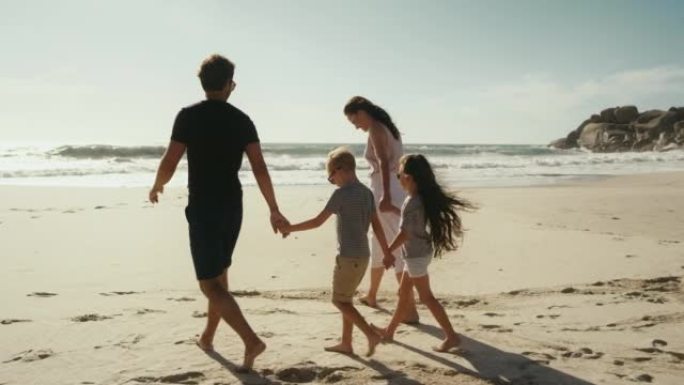 Family holding hands and walking on the beach whil