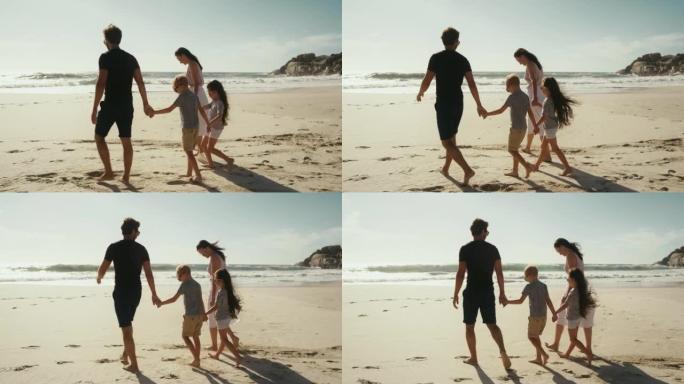 Family holding hands and walking on the beach whil