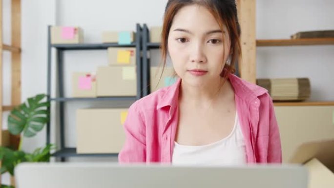 年轻的亚洲企业家女商人在库存上检查产品采购订单，并保存到家庭办公室的笔记本电脑工作中。