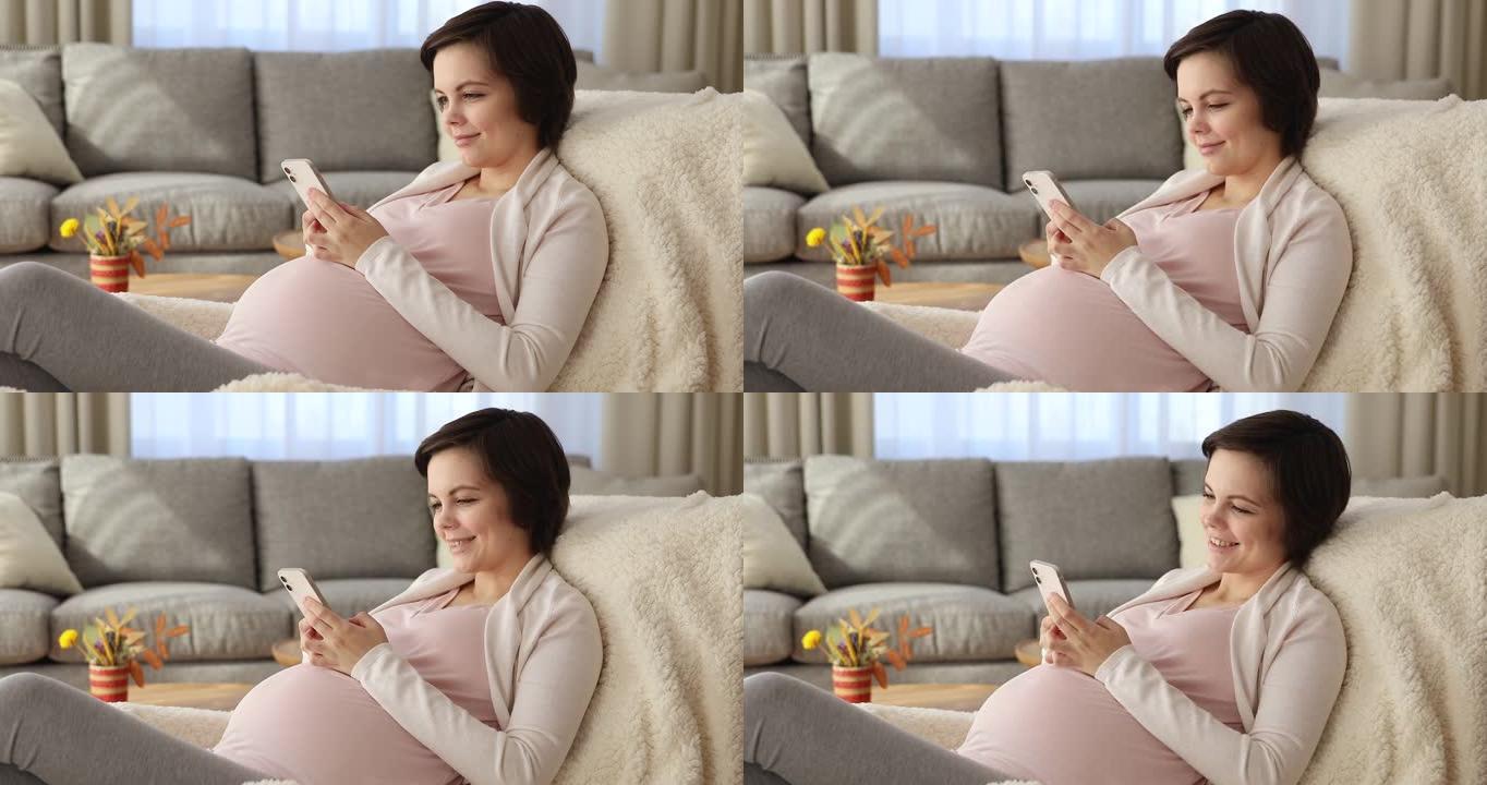 快乐美丽的年轻孕妇使用手机。