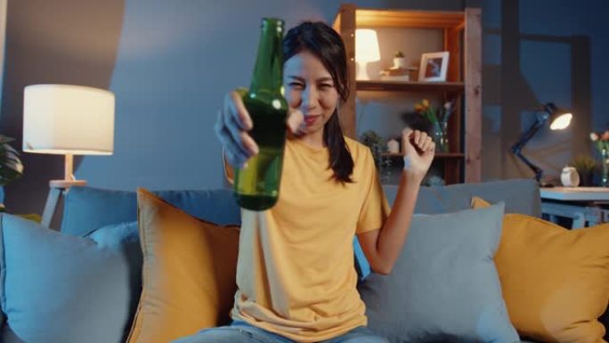 看着相机快乐的年轻亚洲女性在家里的客厅通过在线视频通话与朋友一起在线享受夜间派对活动。