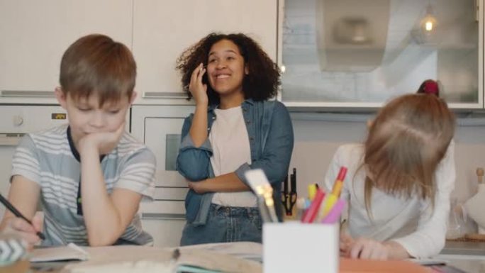 无忧无虑的美国黑人保姆在孩子做作业学习时在手机上聊天