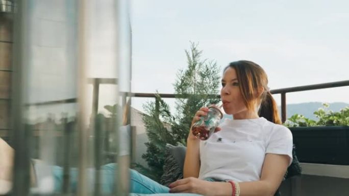 年轻女子喝果汁，在阳台上放松