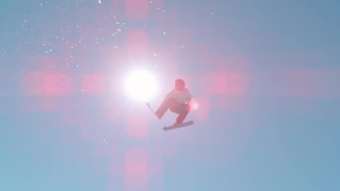 慢动作: 男子滑雪者在白雪皑皑的滑雪区的雪公园跳高空中踢脚
