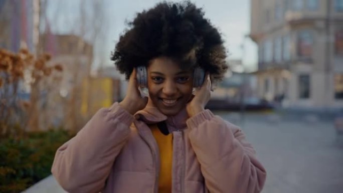 MS肖像拍摄了一个快乐的年轻黑人妇女通过无线耳机听音乐的照片