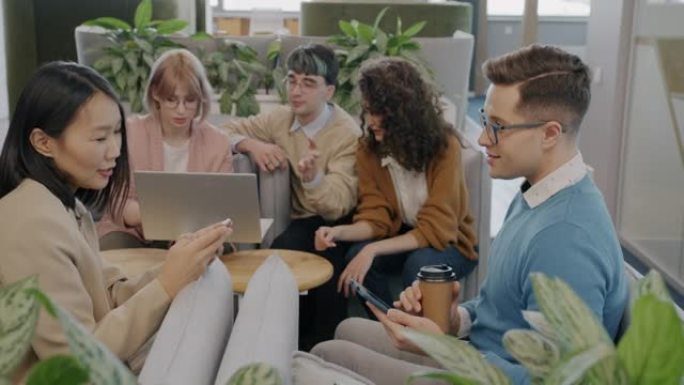 一群在创意办公室谈论和使用笔记本电脑的商人讨论业务