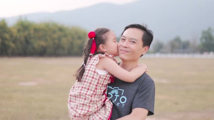 亚洲女孩在公园里亲吻父亲的脸颊