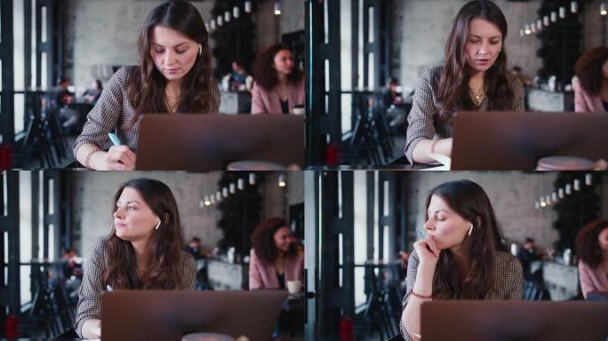 年轻快乐迷人体贴的高加索黑发女性创意作家用笔记本电脑在咖啡馆工作做笔记。
