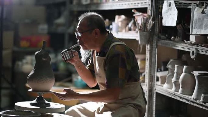 亚洲中国高级陶土艺术家在雕刻家的工作室里用旋转的陶轮吹漆