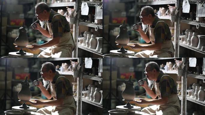 亚洲中国高级陶土艺术家在雕刻家的工作室里用旋转的陶轮吹漆