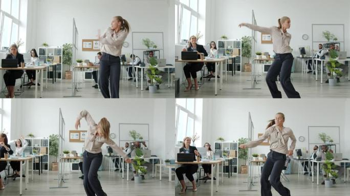 美丽的年轻金发女郎在办公室跳舞，而同事们在背景中拍手