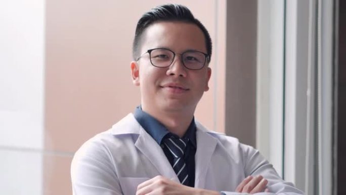 亚洲医生男性经验丰富的医生在诊所独自看着相机时自信地微笑。男医生在视频会议上看。工作骄傲