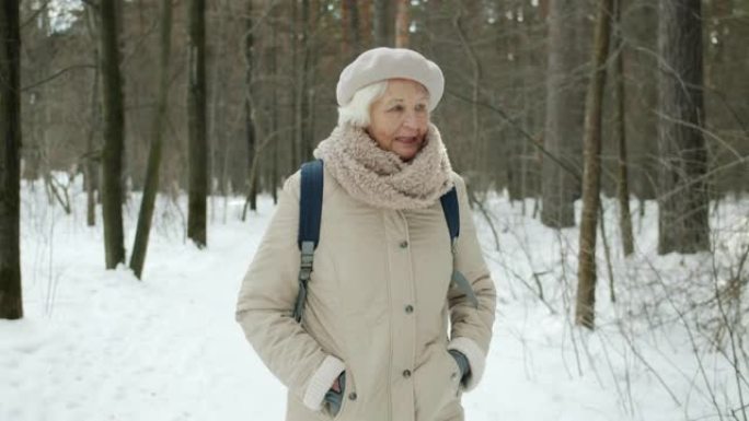 冬天在森林里散步的老妇人享受健康活动的俯仰肖像