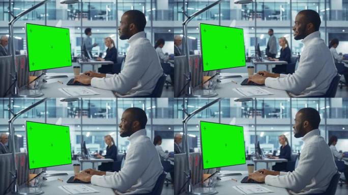 多样化的现代办公室: 英俊的黑人商人使用带有绿屏模拟显示的台式计算机。经理从事电子商务应用程序开发，