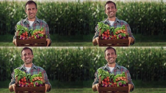 一名男子的肖像向镜头展示了一个装满蔬菜的盒子，背景是绿色的。快乐微笑的男性农民自豪地展示他田间的收成