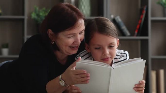 快乐的小女孩和关心的老奶奶一起读纸质书。