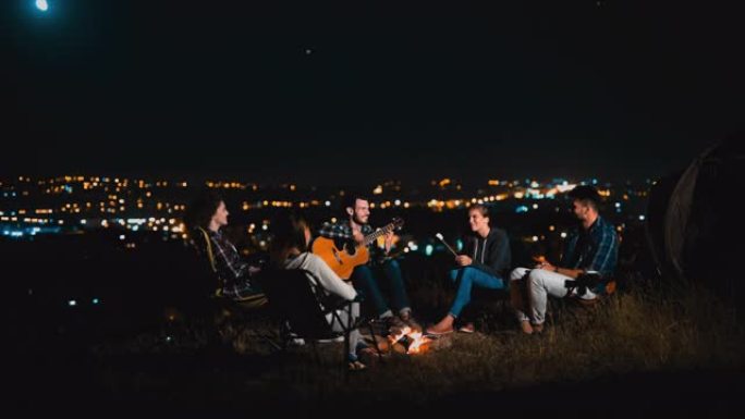 一群在夜间篝火旁弹吉他的朋友