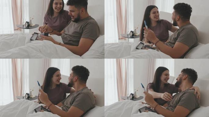爱的拉丁裔夫妇在床上进行怀孕测试