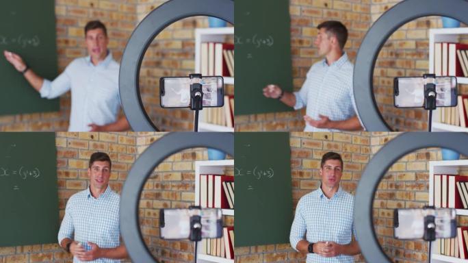 站在黑板上的白人男性数学老师在相机上进行在线课程
