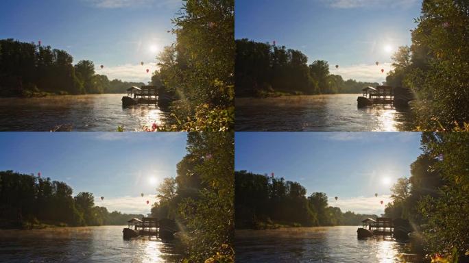 在宁静的河上阳光明媚的天空中飞行的热气球