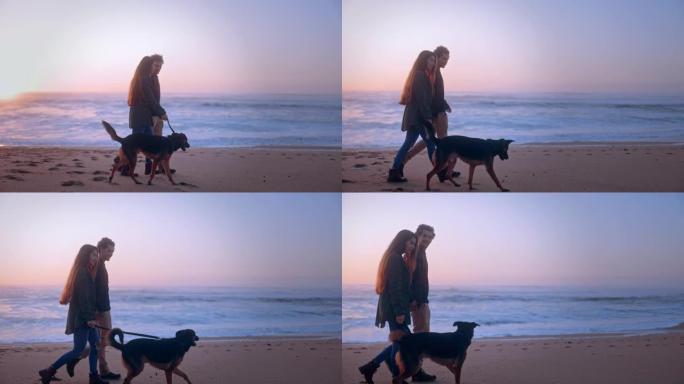 日落时，年轻夫妇在海滩上遛狗