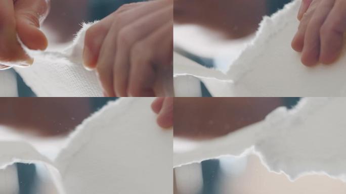工匠造纸大师的宏正在撕下一张手工纸，以控制车间的质量。手工制作的概念，高品质，工匠，意大利制造，传统