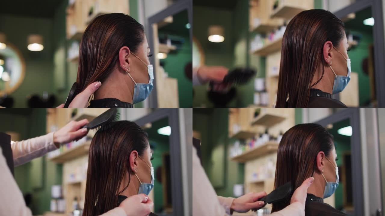 女美发师在美发沙龙戴口罩的女性顾客梳头
