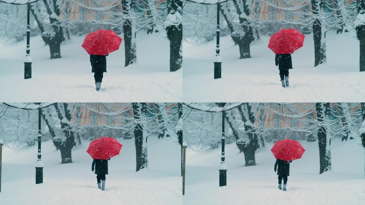 慢动作: 举着红色雨伞的女人沿着空旷的白雪皑皑的大道行走。
