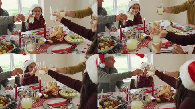 快乐的高加索多代家庭戴着圣诞老人的帽子，吃圣诞大餐