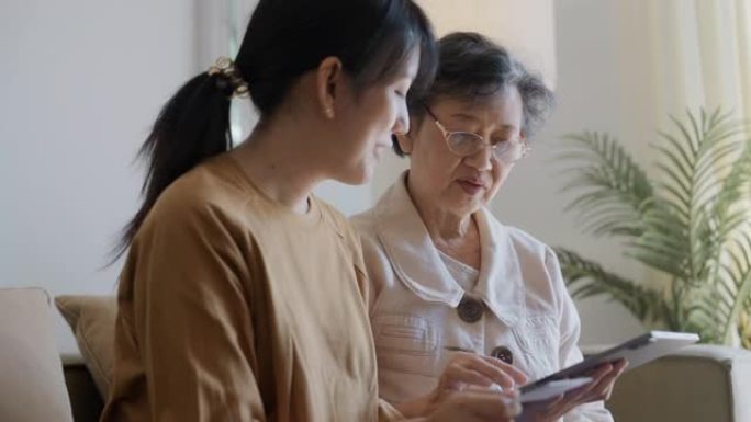 微笑的大妈妈和成年女儿一起使用数字平板电脑购物。