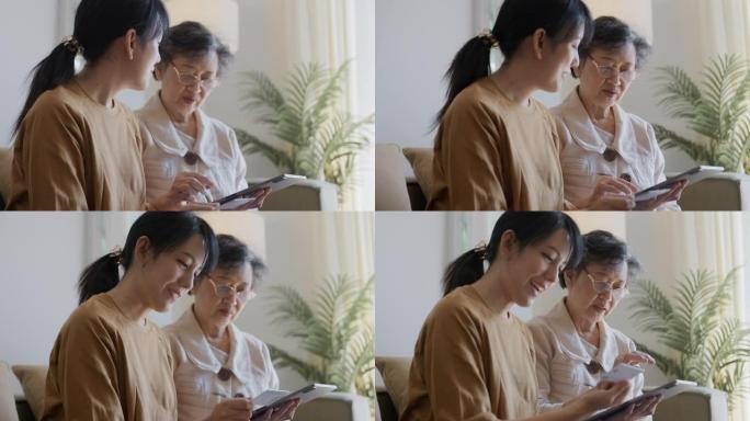 微笑的大妈妈和成年女儿一起使用数字平板电脑购物。