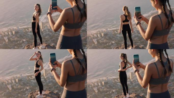 女朋友用智能手机相机在山顶拍照美丽的年轻女子用手机在社交媒体上分享徒步旅行冒险