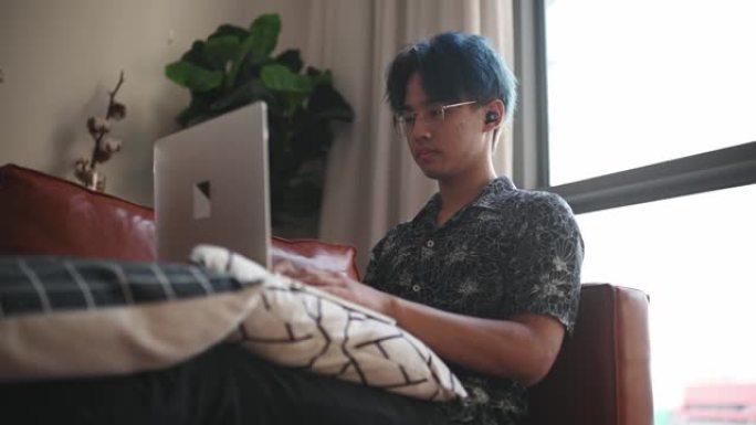 亚洲中国十几岁的男孩在周末使用笔记本电脑坐在客厅的沙发上