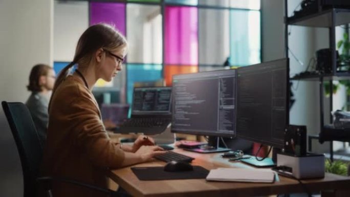 白人女性在台式电脑和笔记本电脑上编码，在宽敞的办公室里有多个显示器。女初级软件工程师，致力于启动移动