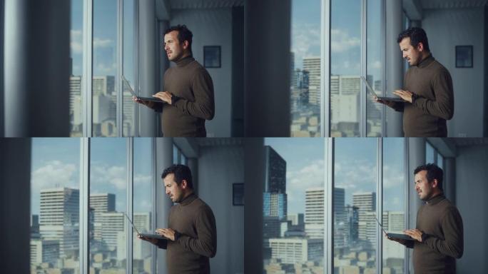 体贴的中东商人站在大城市窗户附近的办公室时使用笔记本电脑。成功的数字企业家从事电子商务投资的数据分析