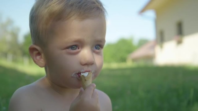 特写: 可爱的小男孩在炎热的日子里在花园的阴影中享受冰淇淋