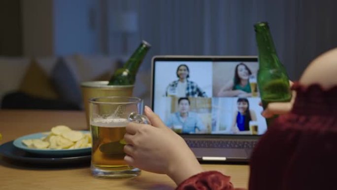 年轻快乐的亚洲女性享受放松之夜派对活动在线庆祝节日，与朋友在家倒杯啤酒和瓶子展示啤酒泡沫通过视频通话
