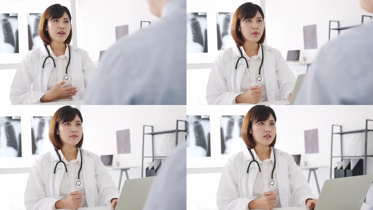 年轻的亚洲女医生使用电脑笔记本电脑正在发表重大新闻谈话，讨论结果或症状与男性患者坐在健康诊所的桌子上